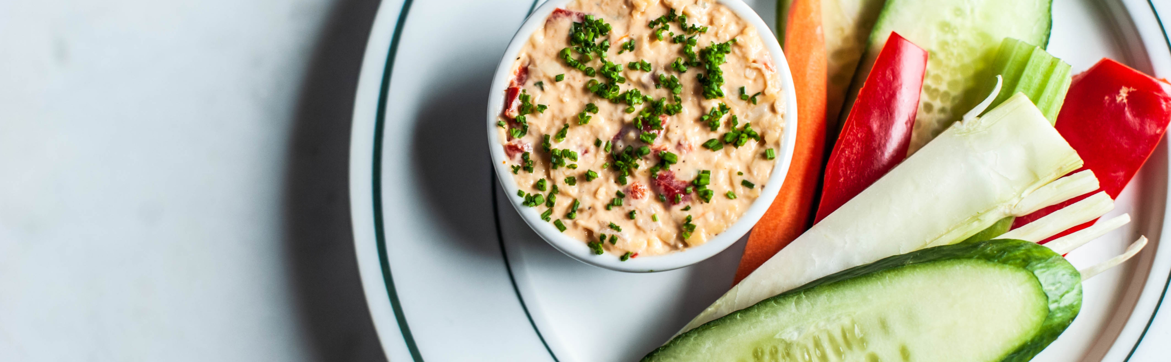 Close up of a platter of food featuring a dip in a small container and assorted vegetables